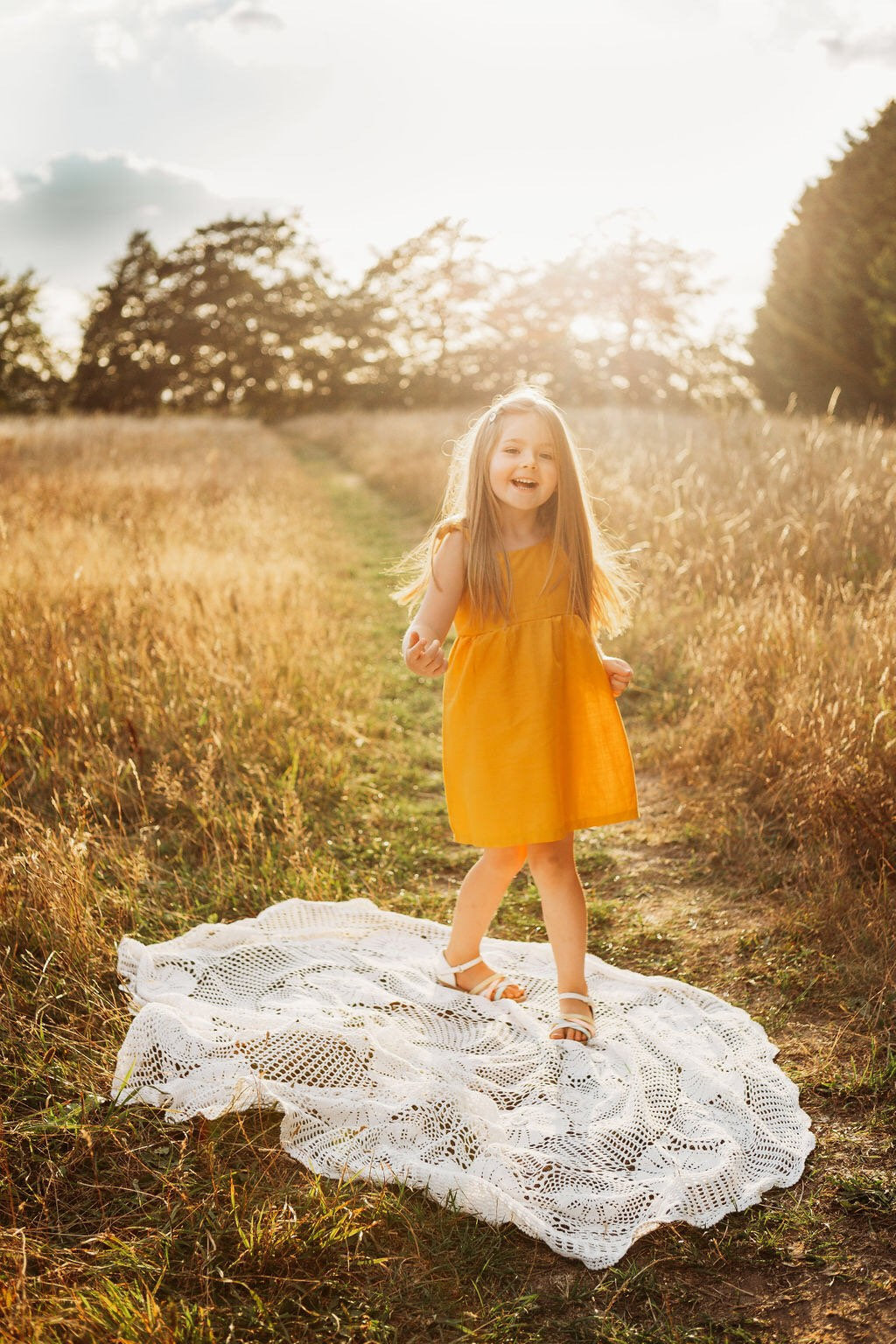girl dancing in her cotton linen dress in mustard in a field with the sun behind handmade adjustable straps sustainable