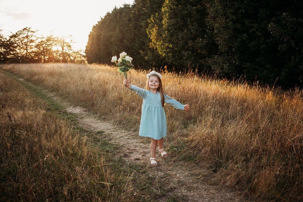 little girl dancing and skipping through meadow with sunset in the background wearing a flower crown wearing her glitter sparkle handmade jersey dress party disco occasion dress inspired frozen elsa sustainable