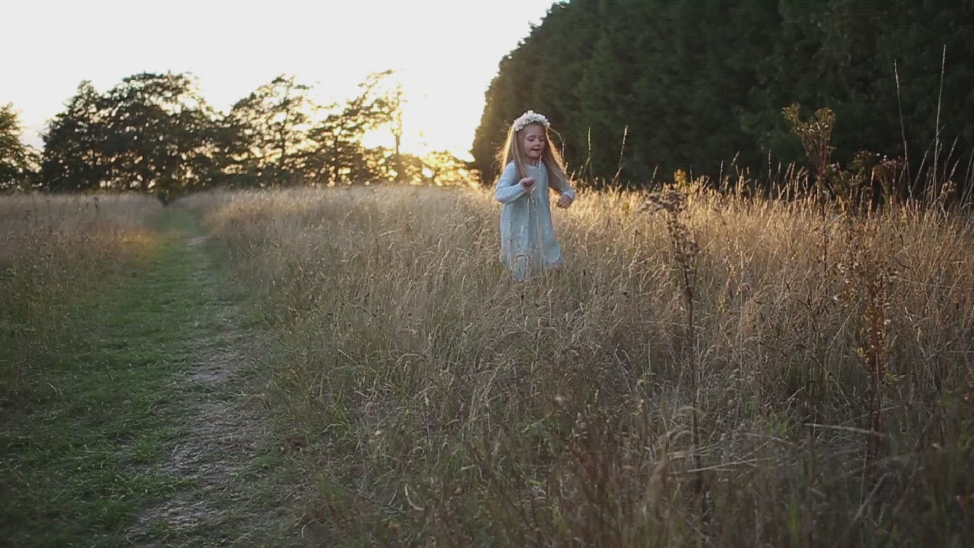 little girl dancing and skipping through meadow with sunset in the background wearing a flower crown wearing her glitter sparkle handmade jersey dress party disco occasion dress inspired frozen elsa sustainable