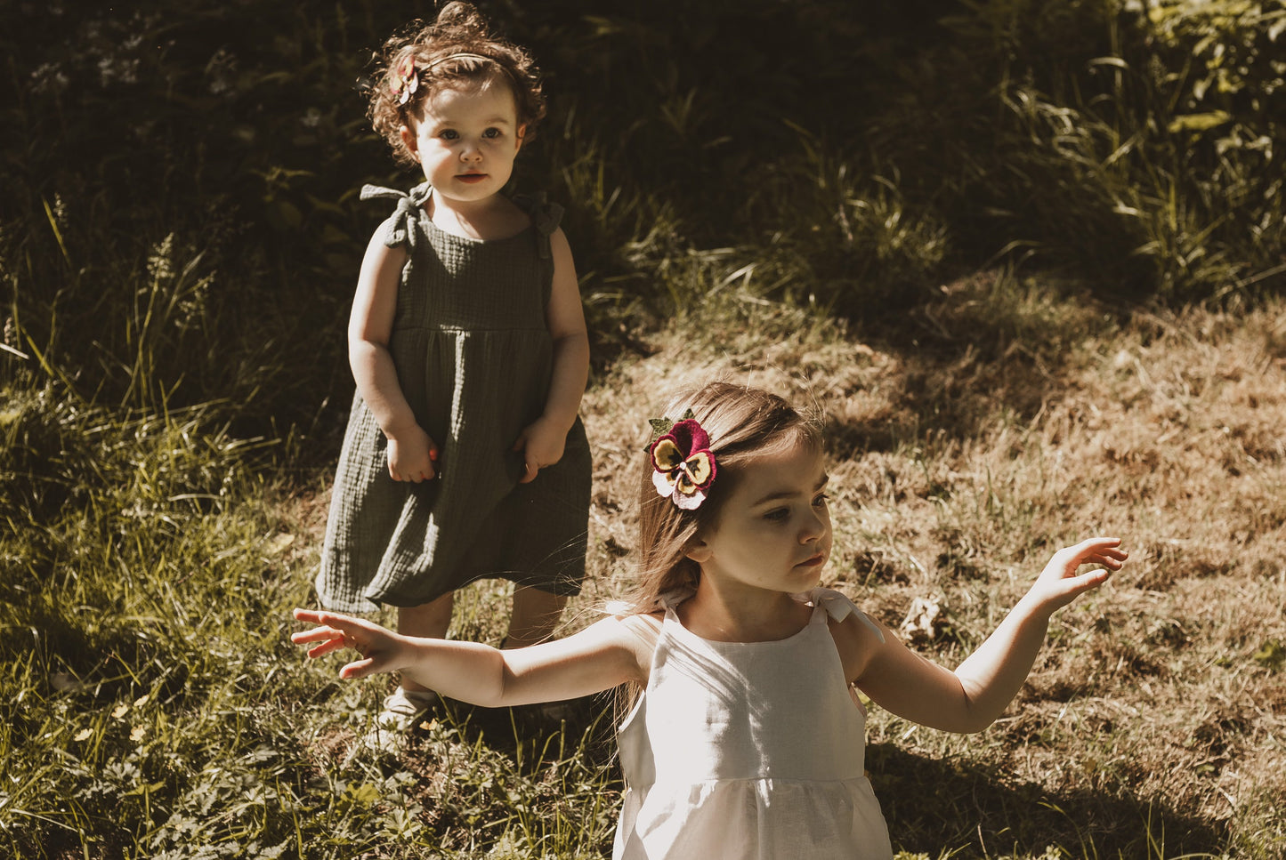 two sisters in garden dancing with adjustable straps dresses summer sustainable handmade bohemian hippy baby clothing
