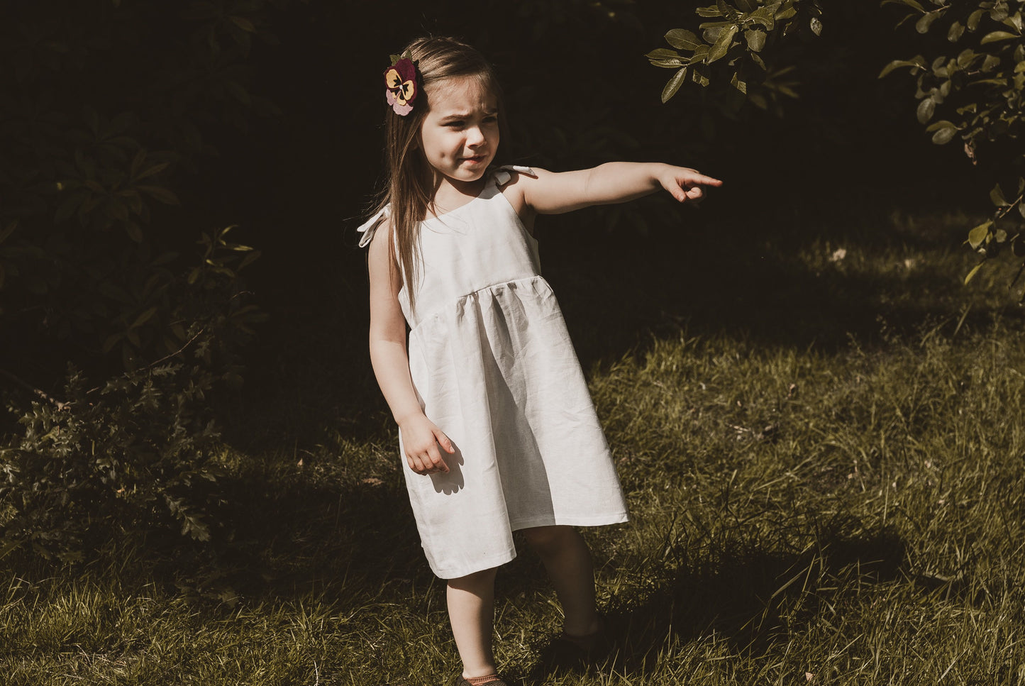 girl stood in garden in summer wearing a cotton linen dress in white adjustable straps sustainable bohemian hippy beach clothing
