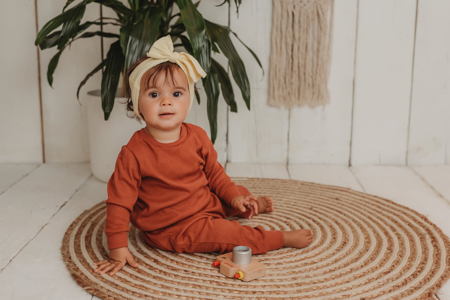 baby girl sits on boho hippy mat with her handmade lounge comfy set cosy in rust orange leggings lounge jumper sustainable unisex 